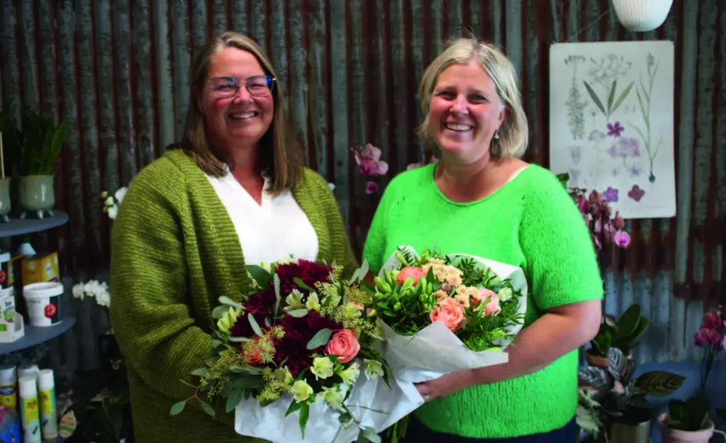 Ansatte i Garnbutikken står med blomster i hendene.